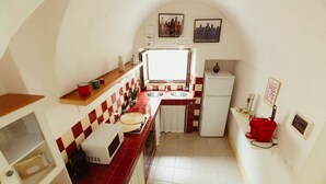 Uma cozinha compacta com micro-ondas, duas pias, geladeira e janela.