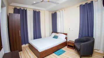 Un dormitorio con cama, una silla, un armario y un ventilador de techo.