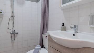 A bathroom with a shower, toilet, and sink.