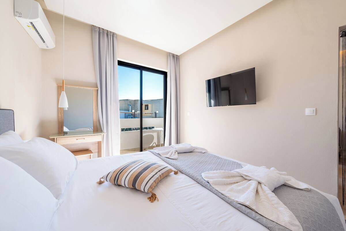 Habitació d'hotel amb llit, televisió, escriptori i finestra amb vistes.
