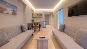 A modern living room with two sofas, a coffee table, and a TV mounted on the wall. - Blue Wave Suites - Ixia (Rhodes)