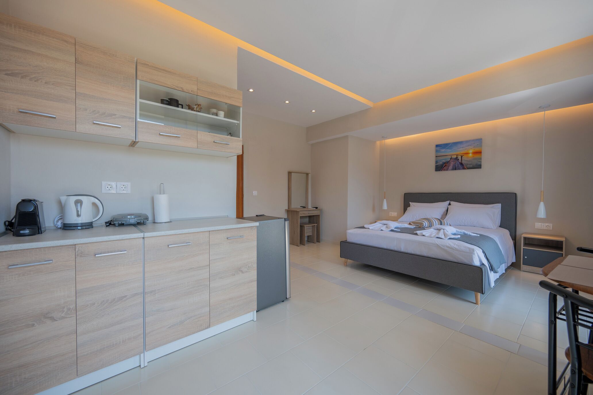 Une chambre moderne avec un grand lit, des tables de chevet, un bureau et un coin cuisine.