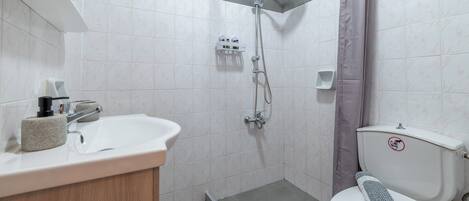 Ein Badezimmer mit Dusche, Toilette, Waschbecken und Handtuchhalter.