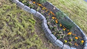Een aangelegde tuin met een stenen rand en diverse bloemen.