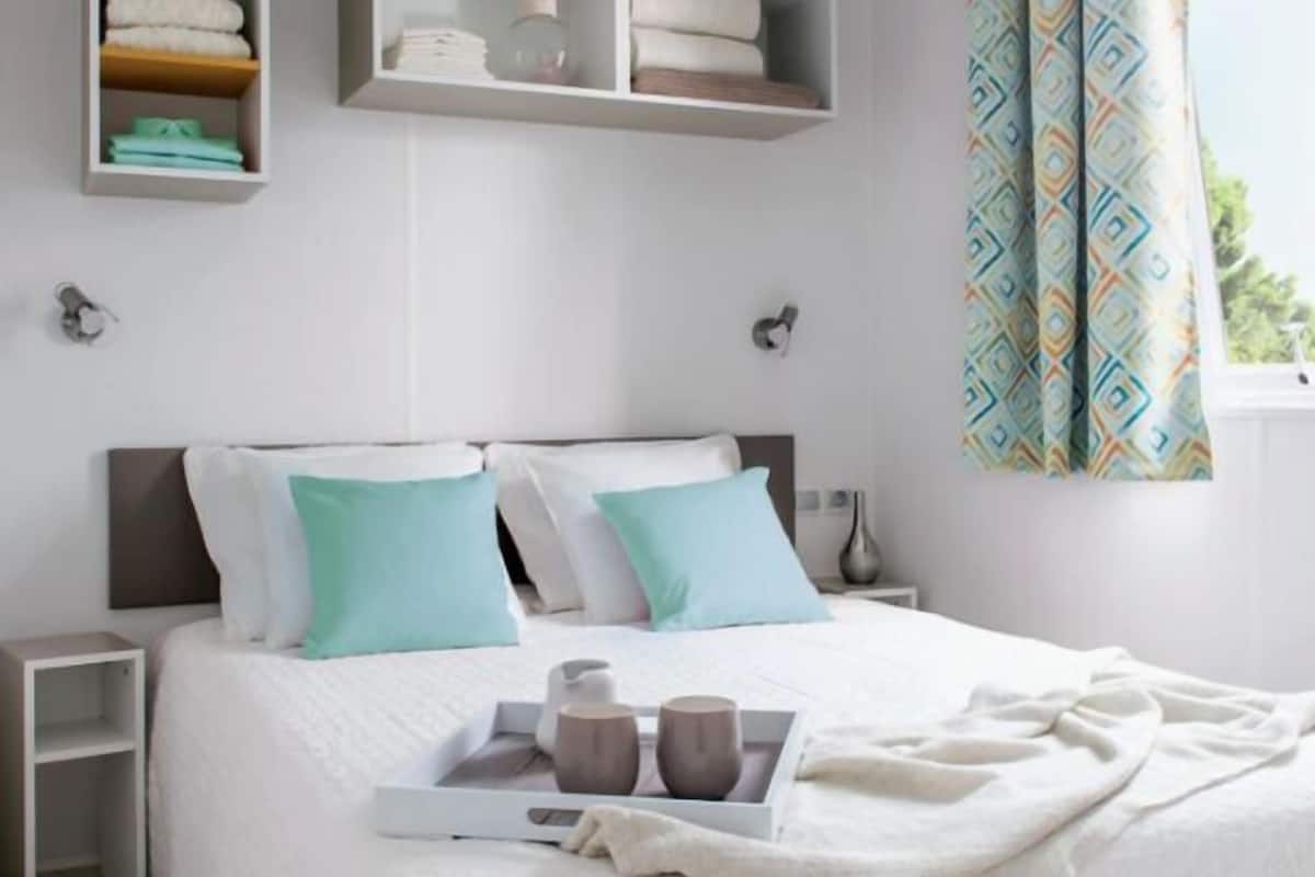 A neatly arranged bedroom with a bed, bedside tables, and built-in shelves.