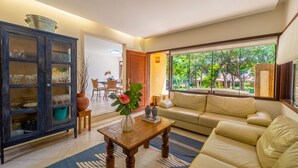 Sala de estar con sofá, una mesa de centro, un aparador con puertas de cristal y vistas al exterior.
