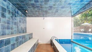 Un baño con suelo de madera, bañera blanca y pared con azulejos azules.