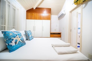 Une chambre à coucher avec un lit, du linge de lit blanc, une armoire en bois et une table de chevet.