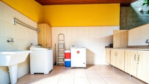 A kitchen with a sink, washing machine, and a small refrigerator.