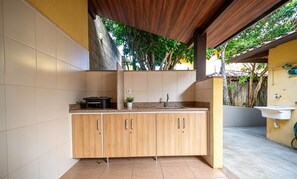 Une cuisine avec des meubles en bois, un plan de travail, un évier et une plante en pot.