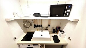A compact kitchenette with a microwave, sink, and built-in washing machine. - Apartment - Arc de Triomphe - 4 people (Paris)