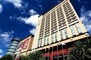 Un hotel alto con varios pisos y una estructura cilíndrica destacada a la izquierda.