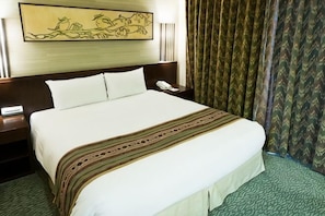 Ein Hotelzimmer mit einem großen Bett, einem Nachttisch mit Telefon und einem Gemälde an der Wand.