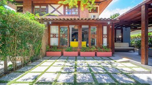 A modern house with a tiled patio, a wooden deck, and a covered outdoor seating area. - Bz87 Casa Churrasqueira 200m da Praia (Buzios)