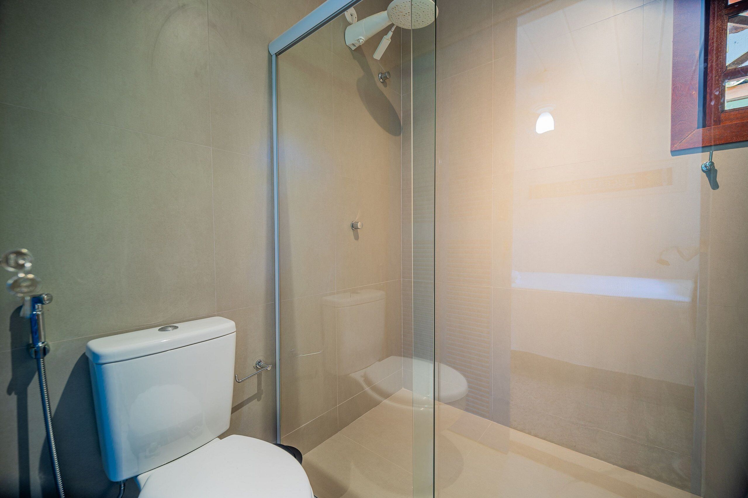A bathroom with a glass shower enclosure, a toilet, and a sink.