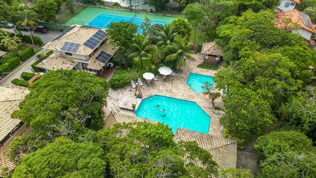 A resort with multiple swimming pools, solar panels on rooftops, and lush greenery. - Bz87 Casa Churrasqueira 200m da Praia (Buzios)