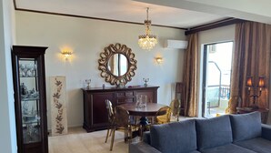 A living room with a dark wooden cabinet, a dining table with chairs, a large mirror, and a chandelier. - Beachfront Paradise (Rethymno)