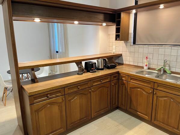 A kitchen with wooden cabinets, a countertop, a sink, and a coffee maker. - Beachfront Paradise (Rethymno)