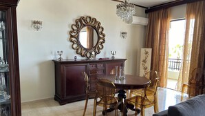 A dining area with a wooden table, chairs, a chandelier, and a large mirror. - Beachfront Paradise (Rethymno)