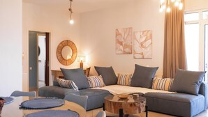 A modern living room with a sectional sofa, a round coffee table, and a dining area with a glass table.