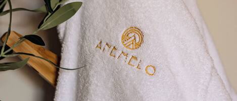 A white towel with embroidered text and a logo, hanging on a wooden surface.