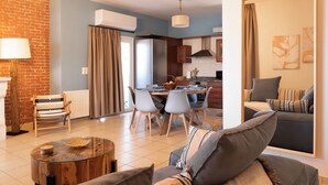 A modern living room with a sofa, a coffee table, and a dining area with a table and chairs.
