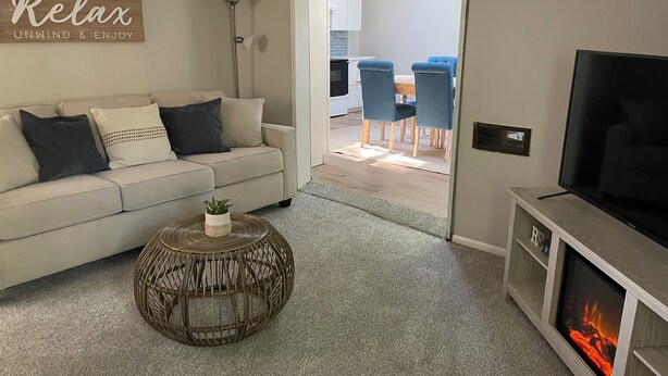 Una sala de estar con un sofá, una mesa redonda de centro, un televisor de pantalla plana y una chimenea.
