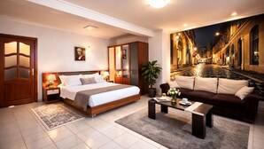 Een moderne hotelkamer met een groot bed, een bank, een salontafel en uitzicht op een straat in de stad 's nachts.