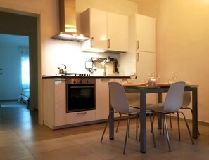 A compact kitchen with white cabinets, a built-in oven, and a dining area with four chairs. - Renovated, located in the city center, and just a stone's throw from the ocean, with parking available (Livorno)