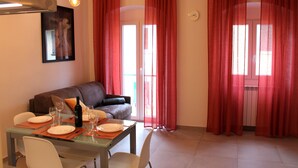 Un espace repas comprenant une table en verre, des chaises et un canapé.