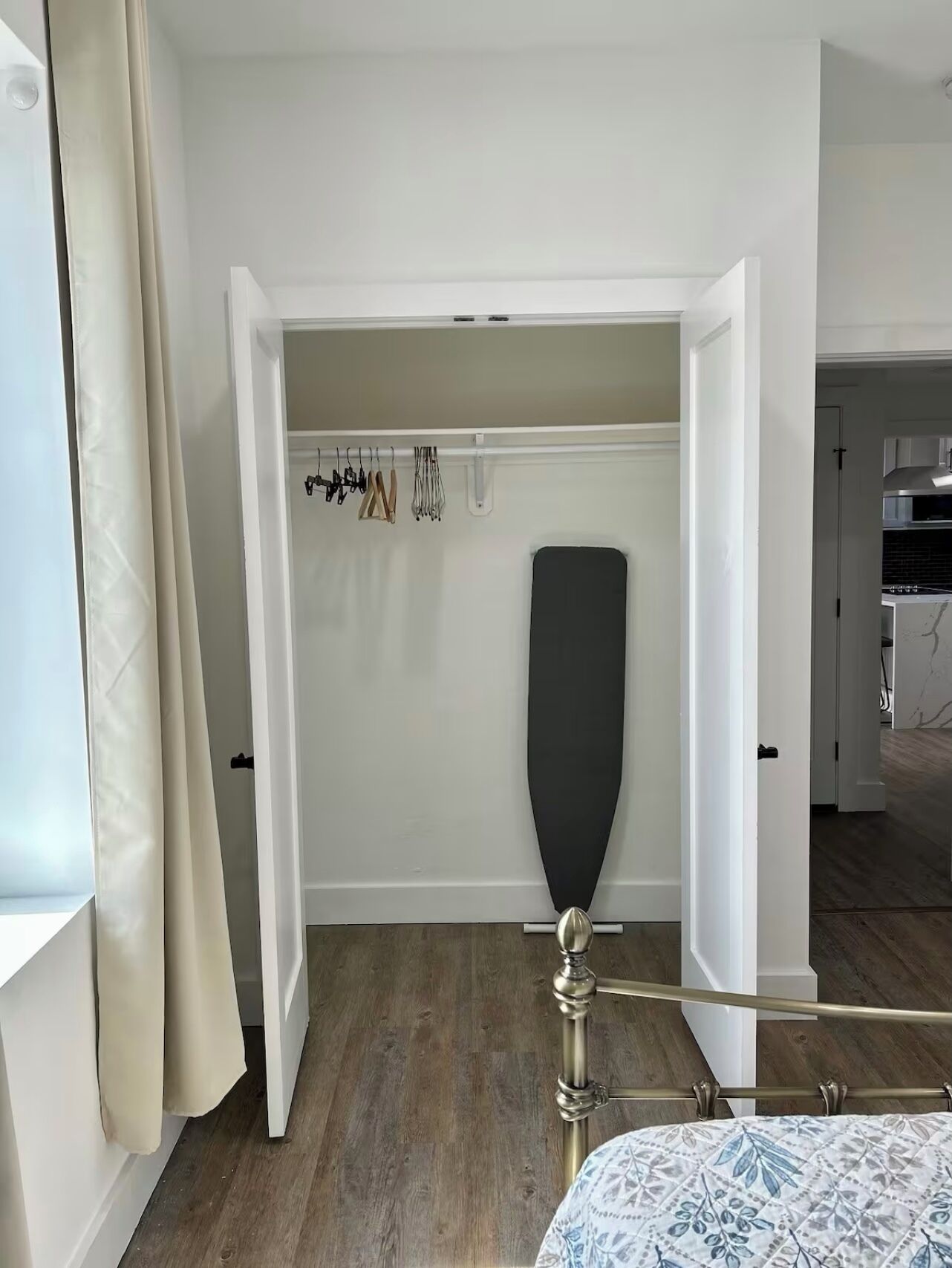 A bedroom with a bed, a wardrobe, and a hanging rack with clothes.
