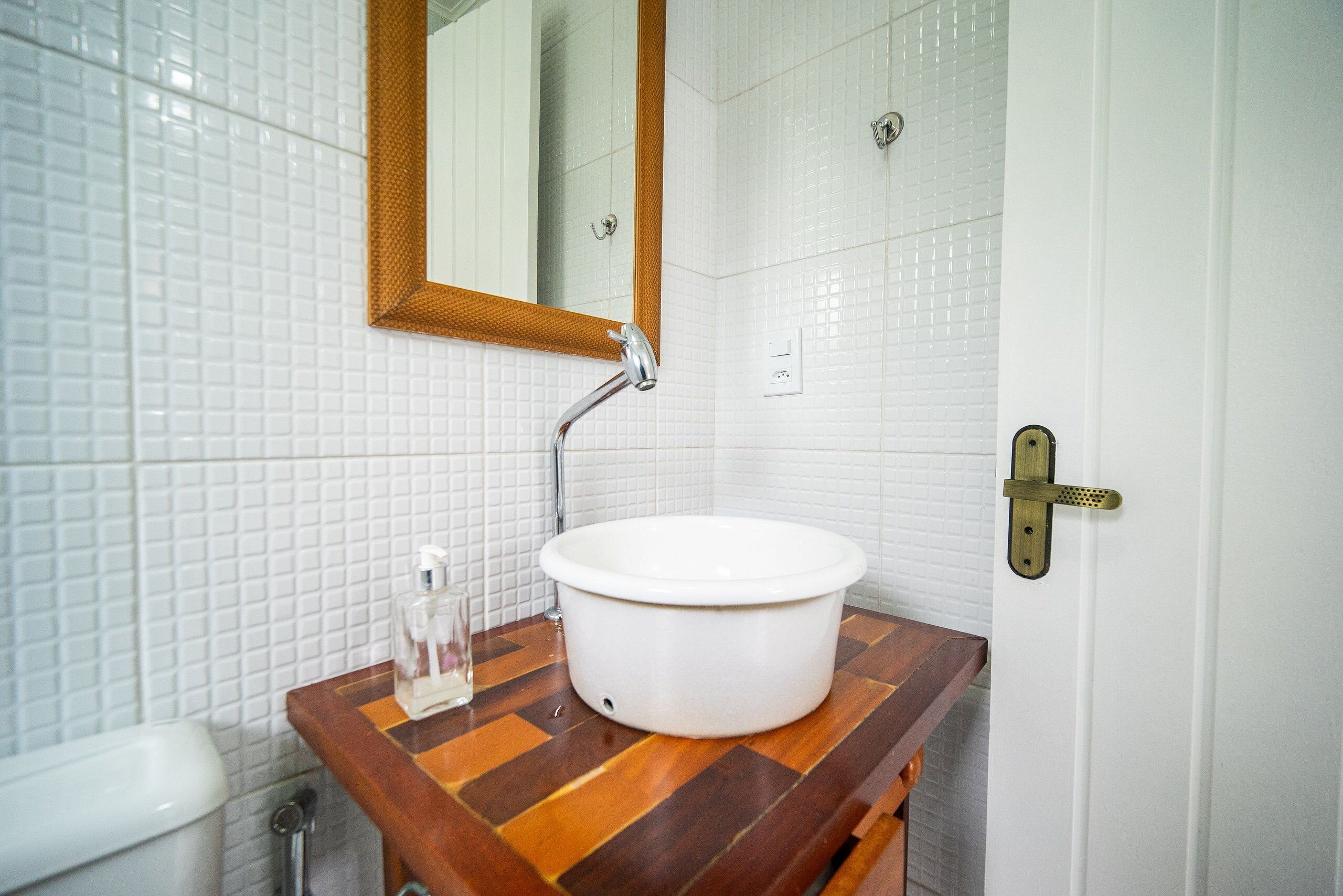 A bathroom with a white sink, wooden countertop, and a mirror.