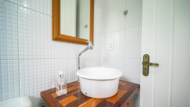A bathroom with a white sink, wooden countertop, and a mirror. - Bz88 250 metros da praia Casa 4 quartos (Buzios)