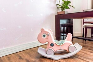 A pink rocking horse in a room with a wooden floor and a potted plant in the background. - Xiyue Holiday Hotel (Chongqing Liangping New City Branch) (Chongqing)