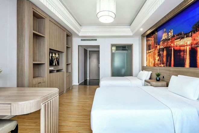 Ein Hotelzimmer mit Bett, Schreibtisch, Kleiderschrank und einem großen Fenster mit Blick auf die Stadt.