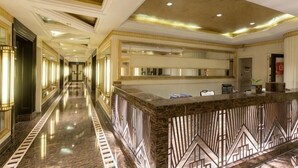 A hotel lobby with a marble reception desk, a long corridor, and a high ceiling with recessed lighting. - Xiyue Holiday Hotel (Chongqing Liangping New City Branch) (Chongqing)