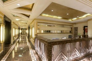 A hotel lobby with a marble reception desk, a long corridor, and a high ceiling with recessed lighting. - Xiyue Holiday Hotel (Chongqing Liangping New City Branch) (Chongqing)