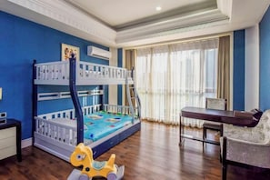 A bunk bed with a desk and chair, a rocking horse, and a window with curtains.