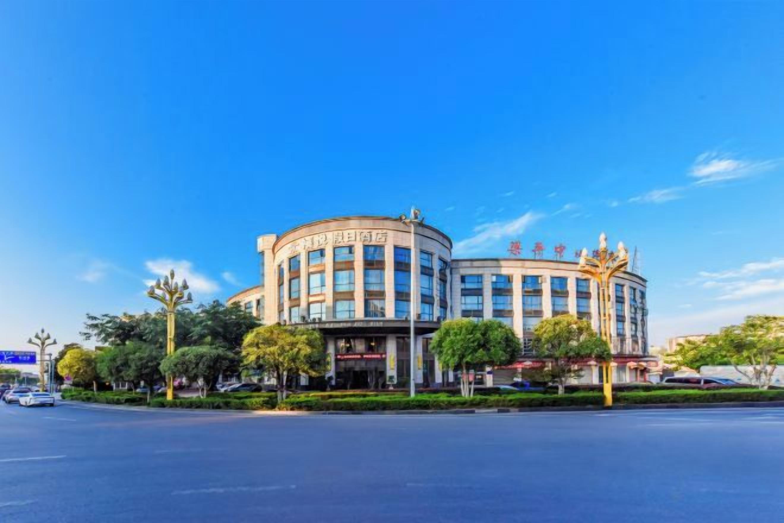 A multi-story building with a circular facade, a prominent entrance, and a clear blue sky.