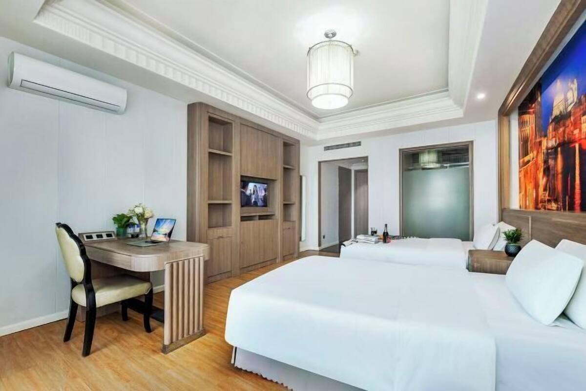Een hotelkamer met een bed, een bureau, een televisie en een schilderij.