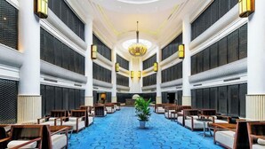 A hotel lobby with a blue carpet, wooden chairs, and a chandelier. - Xiyue Holiday Hotel (Chongqing Liangping New City Branch) (Chongqing)