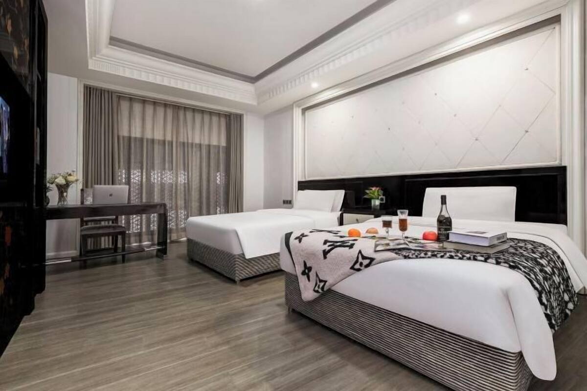 Een hotelkamer met twee bedden, een bureau en een groot raam met gordijnen.