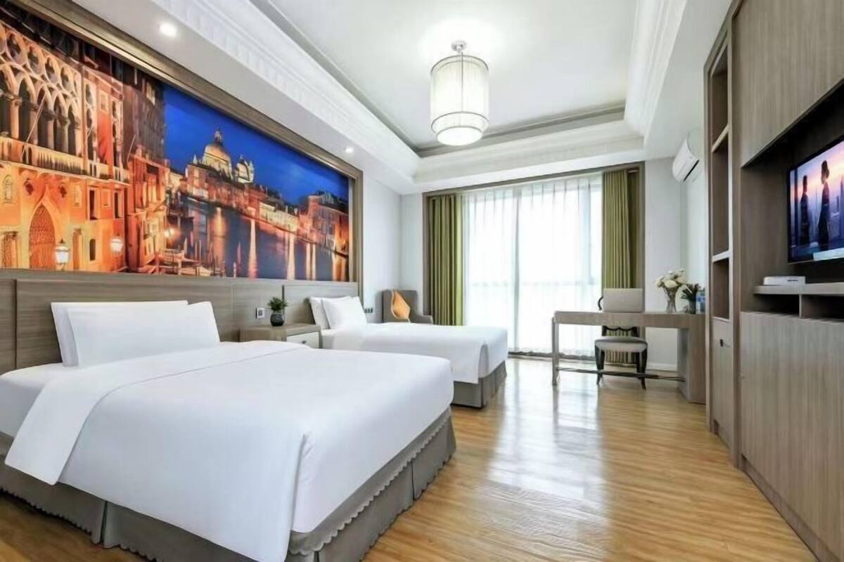 Een hotelkamer met twee bedden, een televisie, een bureau en een groot muurschildering.