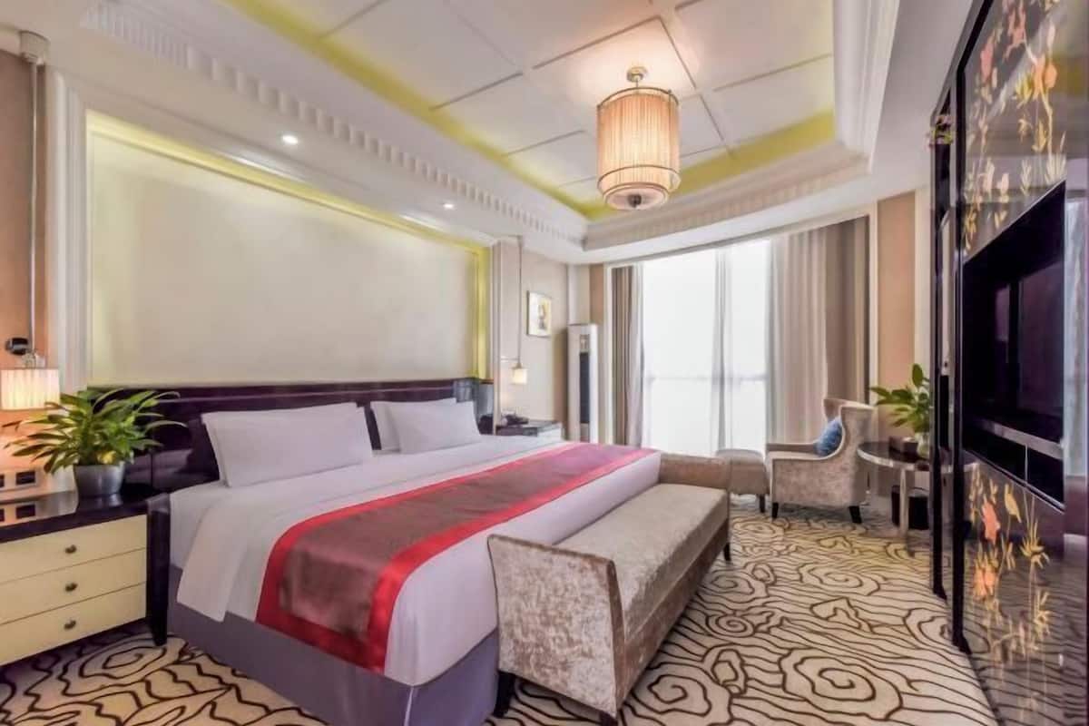 Een hotelkamer met een groot bed, nachtkastjes, een televisie en een bank.