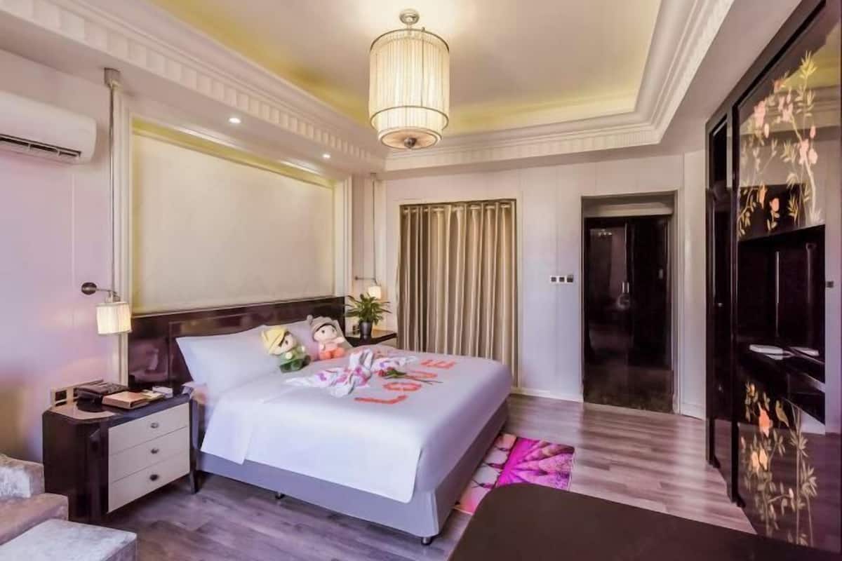 Een hotelkamer met een bed, nachtkastje, bedlampje en een grote spiegel.
