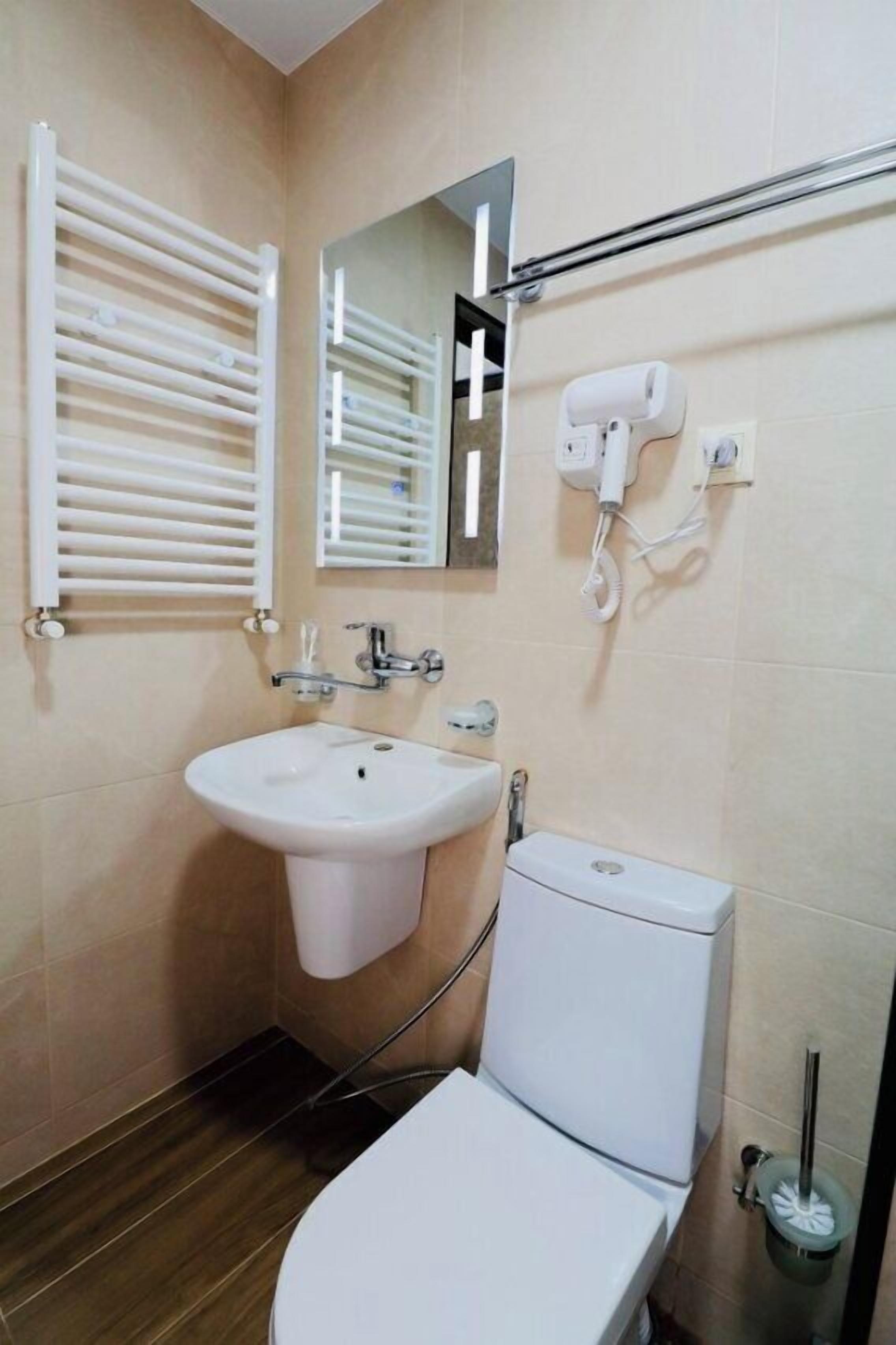 Een kleine badkamer met een wit wastafel, toilet, spiegel en handdoekhouder.
