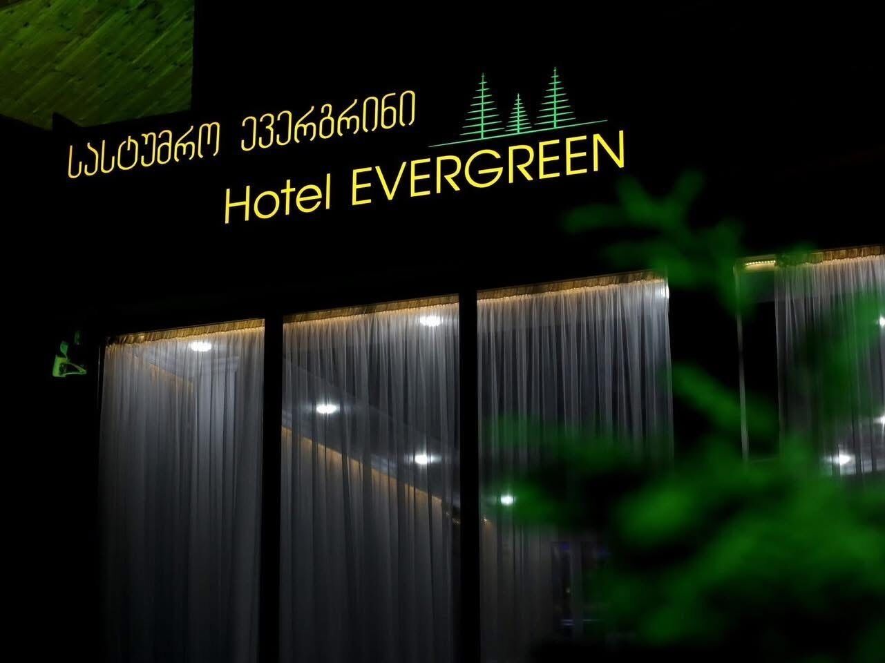 Een hotelentree met verticale gordijnen en een bordje waarop 