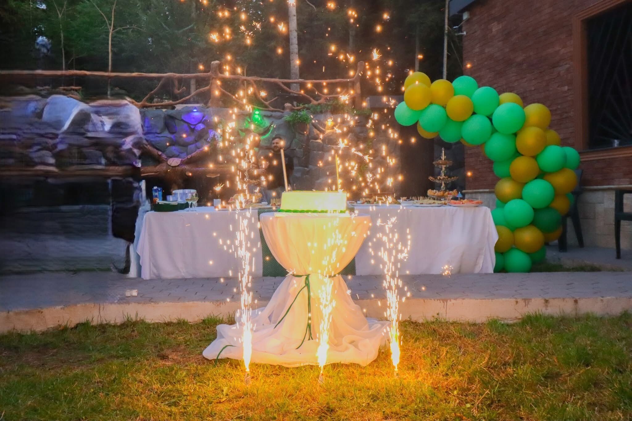 Evento al aire libre con una mesa preparada para una celebración, decorada con globos y un pastel.