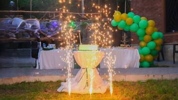 An outdoor event with a table set for a celebration, decorated with balloons and a cake.