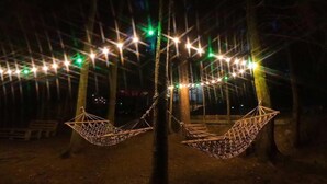 Two hammocks suspended from a tree, with string lights above them. - Hotel EverGreen (Borjomi)